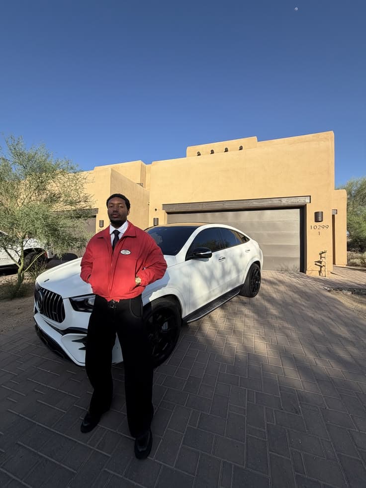 Somebody standing by a white car outside a house